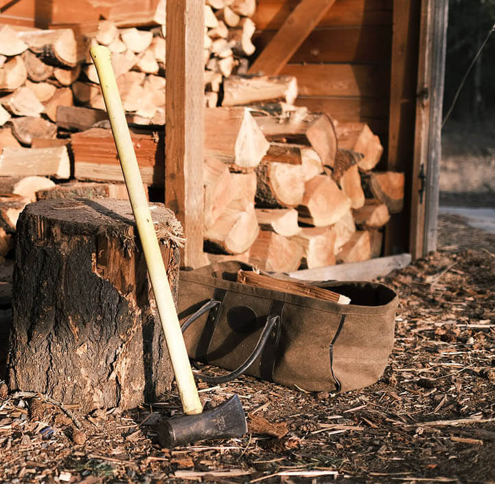 Bijl leunt tegen een hakblok bij een open houtschuur