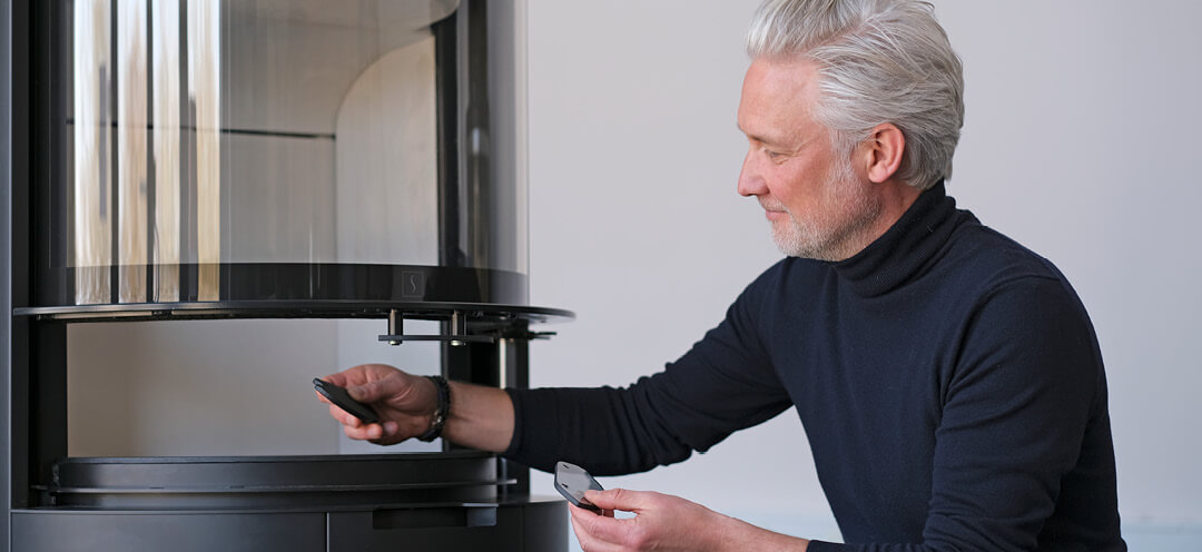 Man van middelbare leeftijd in hooggesloten trui ontwerper Niels Kjeldsen toont glazen handgrepen voor open haard Scan 87