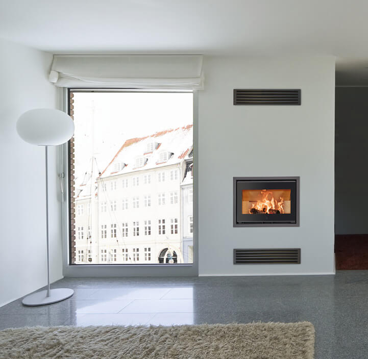 Zwarte inzethaard met vlammen Scan 1005 verzonken in de muur in een witte woonkamer met grote ramen