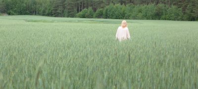 Blonde vrouw in witte jurk staande in een groen veld