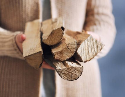 Vrouw in beige vest met hout in haar handen